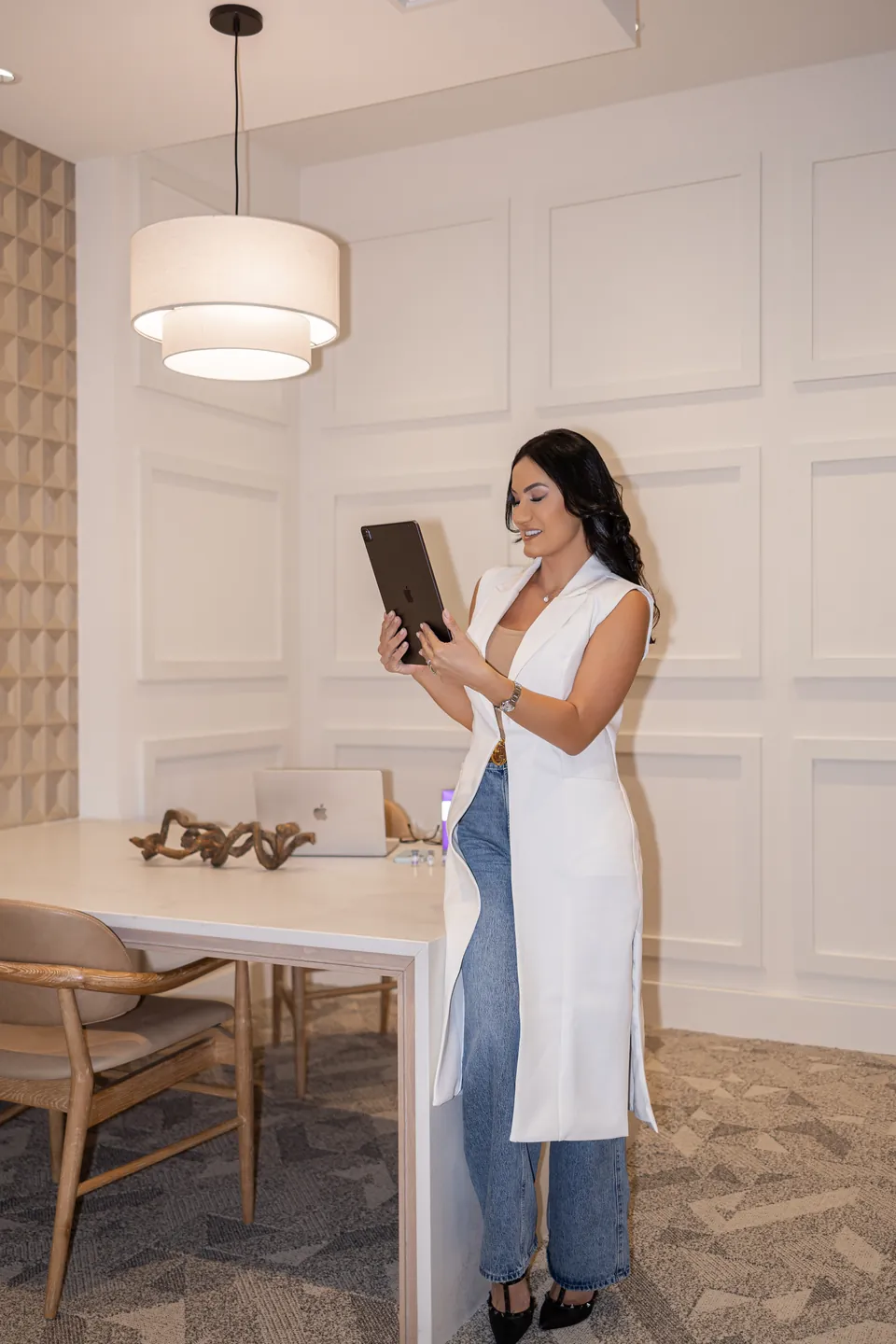Bianca standing with a tablet in a white paneled room